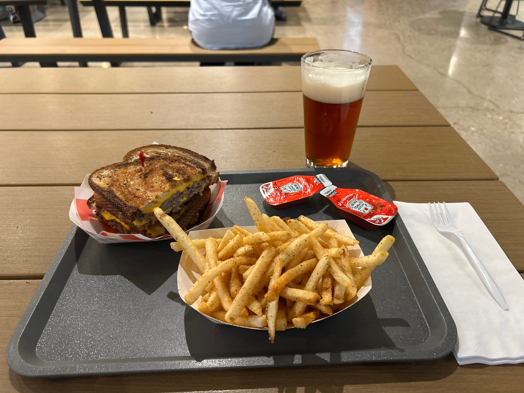 burger, fries, ketchup packets, beer, tray table