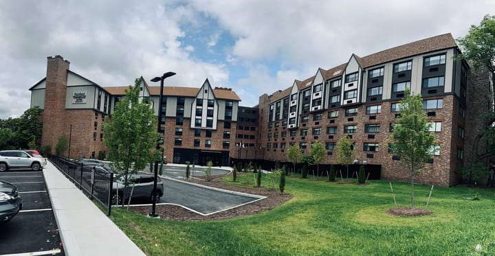 hotel front facade, trees, sidewalk, driveway